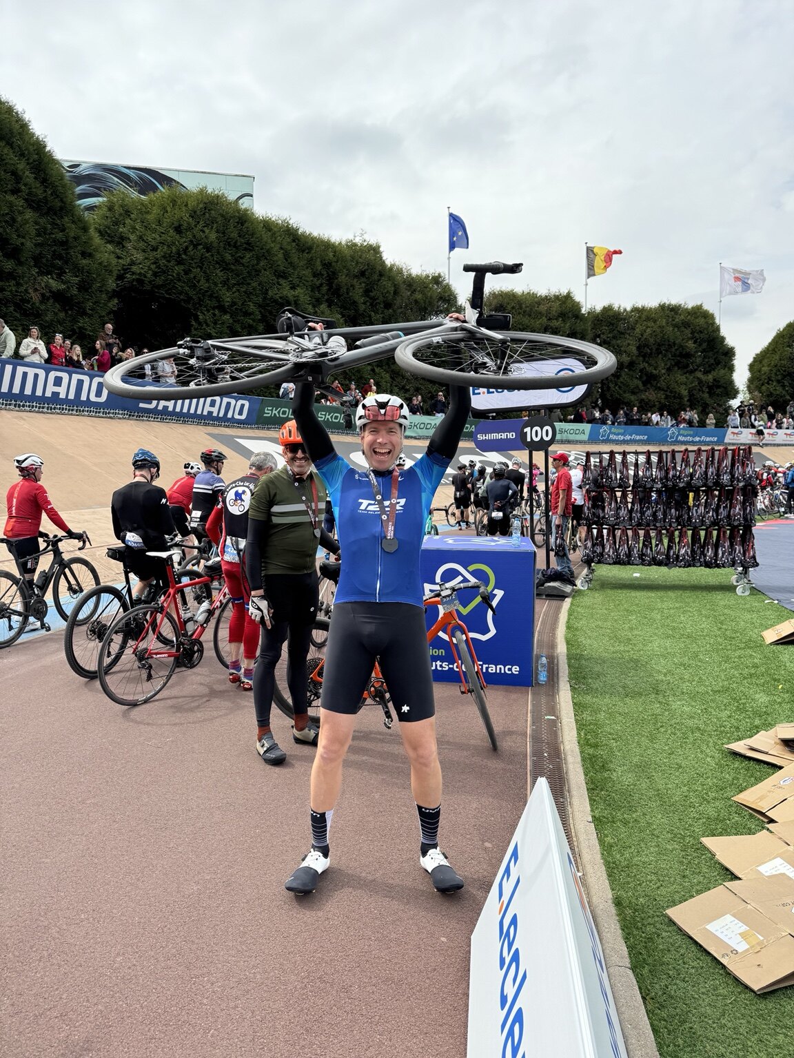 Carlo hebt im Velodrom von Roubaix sein Fahrrad über den Kopf