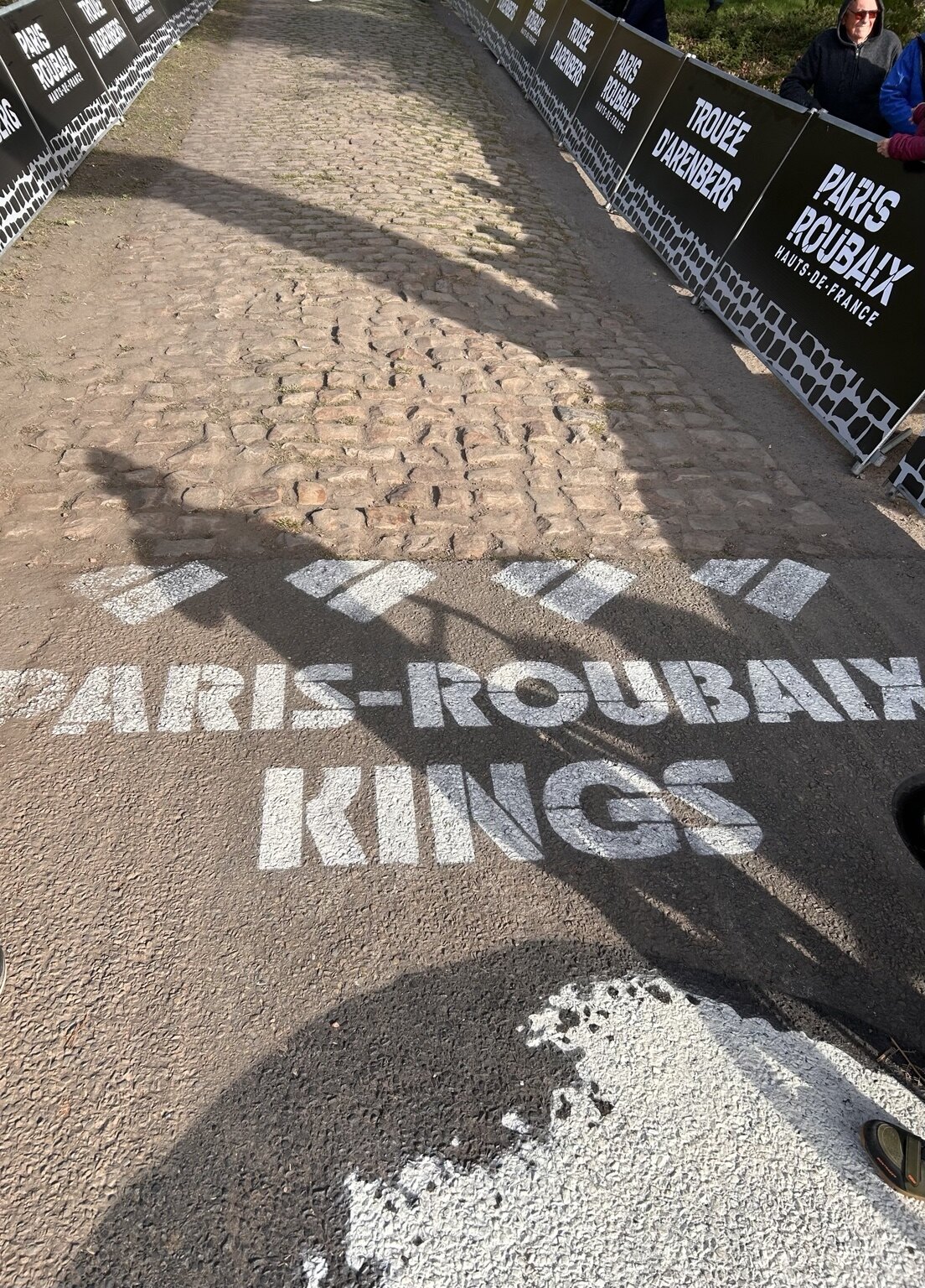 Paris–Roubaix Kings Schriftzug und Schatten eines Fahrrads auf dem Kopfsteinpflaster